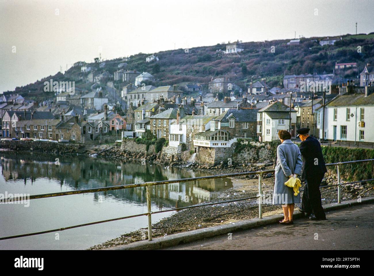 Mann und Frau blicken auf den Hafen, Mousehole, Cornwall, England, Großbritannien November 1961 Stockfoto