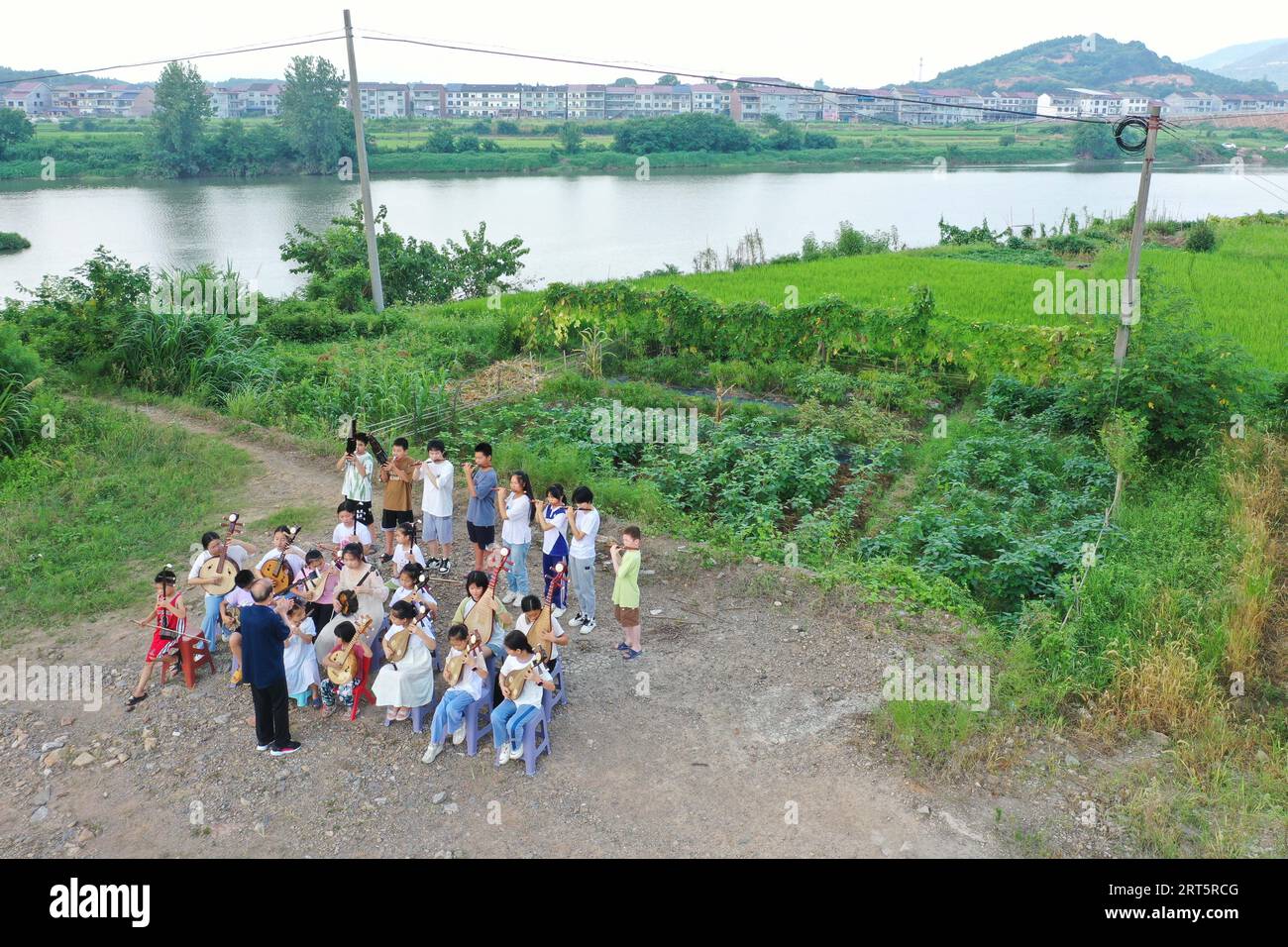 Changsha. August 2023. Dieses Luftbild, das am 12. August 2023 aufgenommen wurde, zeigt Li Shuyou und Studenten, die ein Open-Air-Ensemble im Dorf Jiantouzhou in der Stadt Liling, der zentralchinesischen Provinz Hunan, aufführen. ZU GEHEN MIT 'Across China: 79-jähriger Lehrer schlägt Akkord mit 'zurückgelassenen' Kindern durch Musik' Credit: Xue Yuge/Xinhua/Alamy Live News Stockfoto