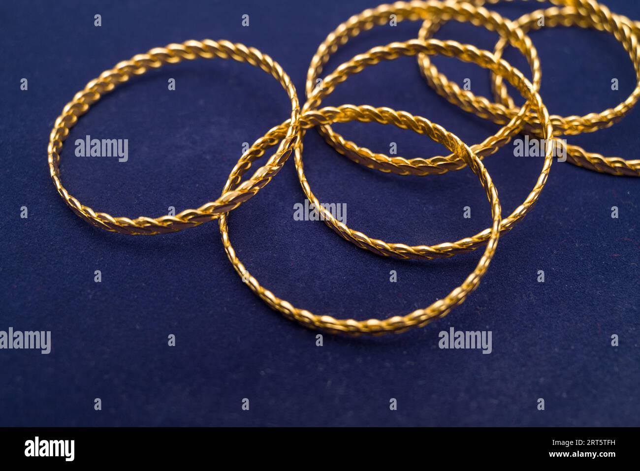 24k (24 Karat) Türkisch Gold Twist Armband steht in einem Haufen auf einem dunkelblauen Hintergrund im Goldladen Stockfoto