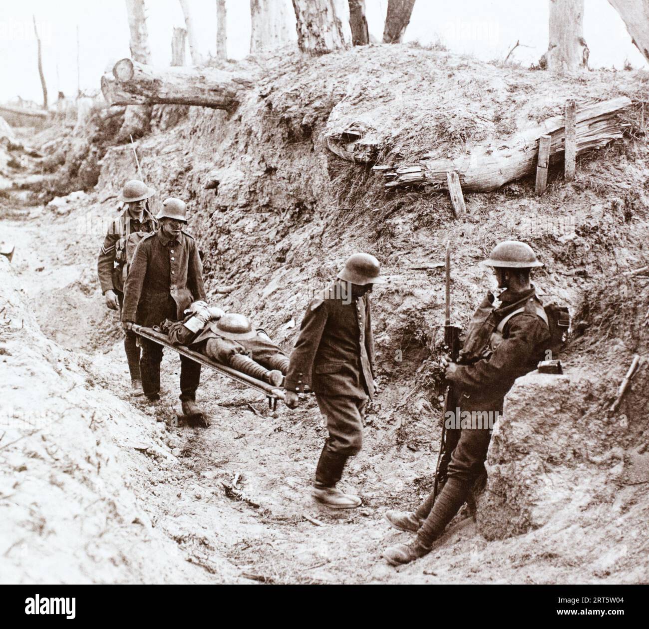 Gefangene deutsche Soldaten unter Bewachung mit einem verwundeten britischen Soldaten auf einer Liege nach Kämpfen bei Bourlon Wood an der Westfront während des Ersten Weltkriegs. Stockfoto