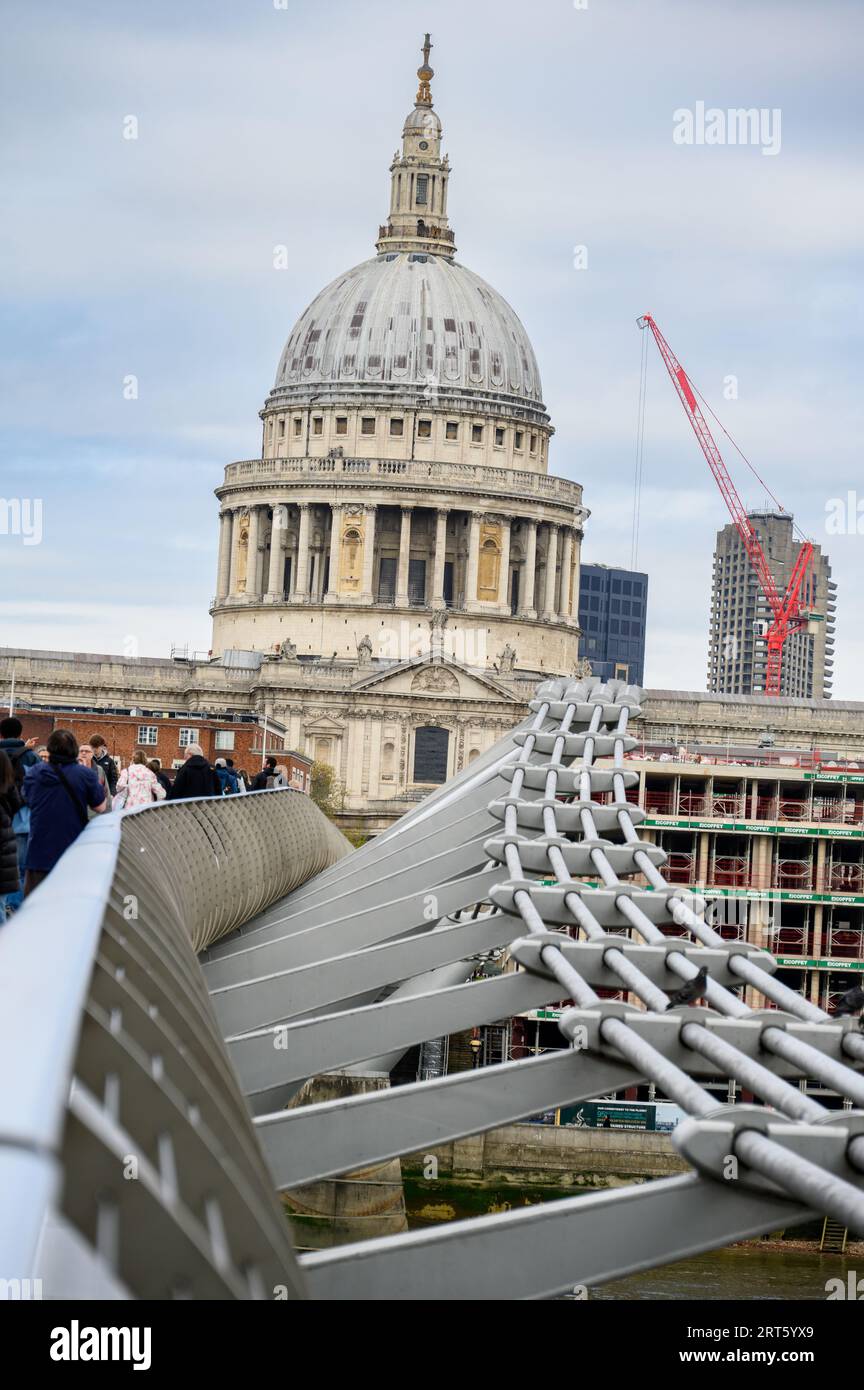 LONDON - 24. April 2023: St Paul's Cathedral, eingerahmt von der Millenniums Bridge und einem entfernten roten Baukran in einem einzigartigen Stadtblick. Stockfoto
