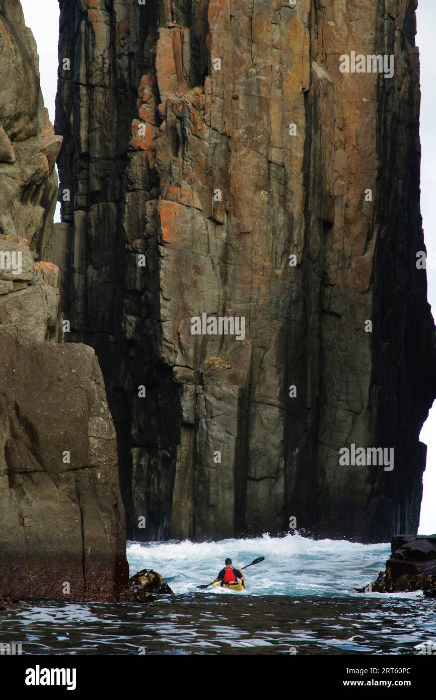 Ein Seekajaker paddelt zwischen Meeresstapeln, Tasmanische Halbinsel, Tasmanien, Australien. Stockfoto