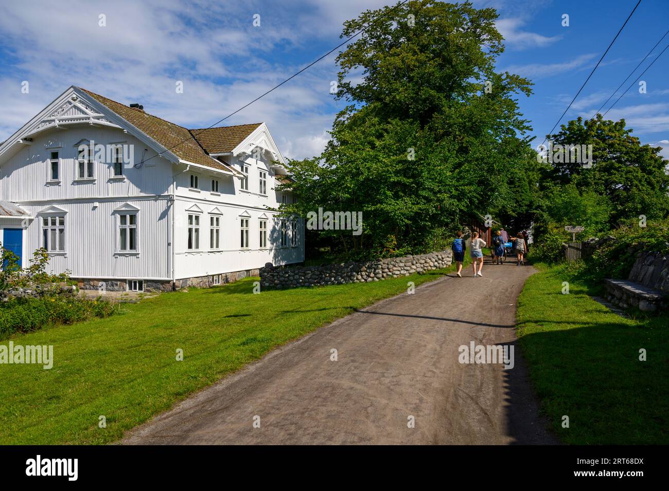 Urlauber spazieren und radeln auf der Strecke durch die wichtigsten Bauernhöfe auf der Insel Jomfruland, einem hellen, sonnigen Sommertag, Telemark, Norwegen. Stockfoto
