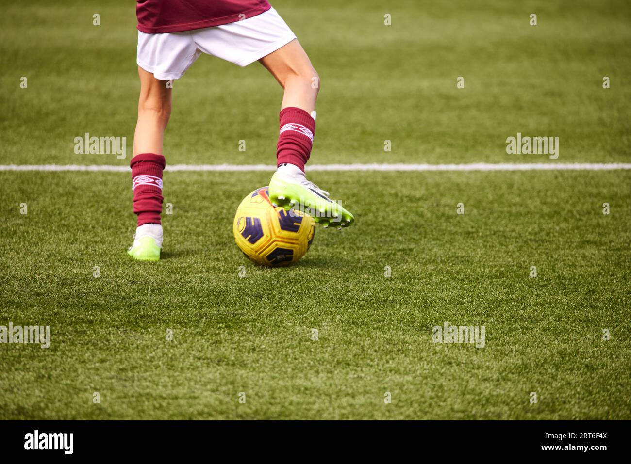 Nahaufnahme der Füße, die Fußball spielen, in West Ham Farben Stockfoto