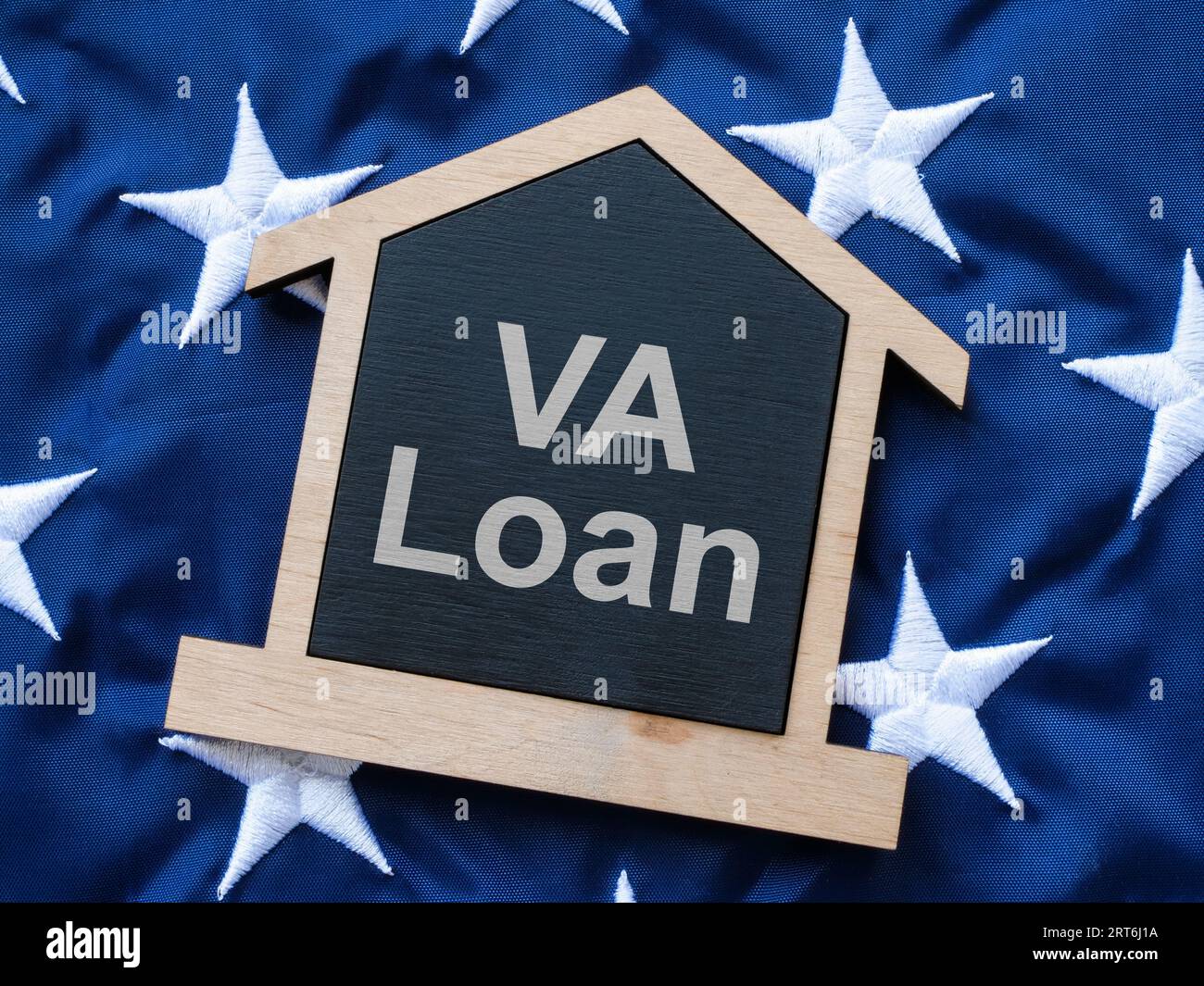 USA-Flagge und ein Hausmodell mit der Inschrift VA Loan. Stockfoto