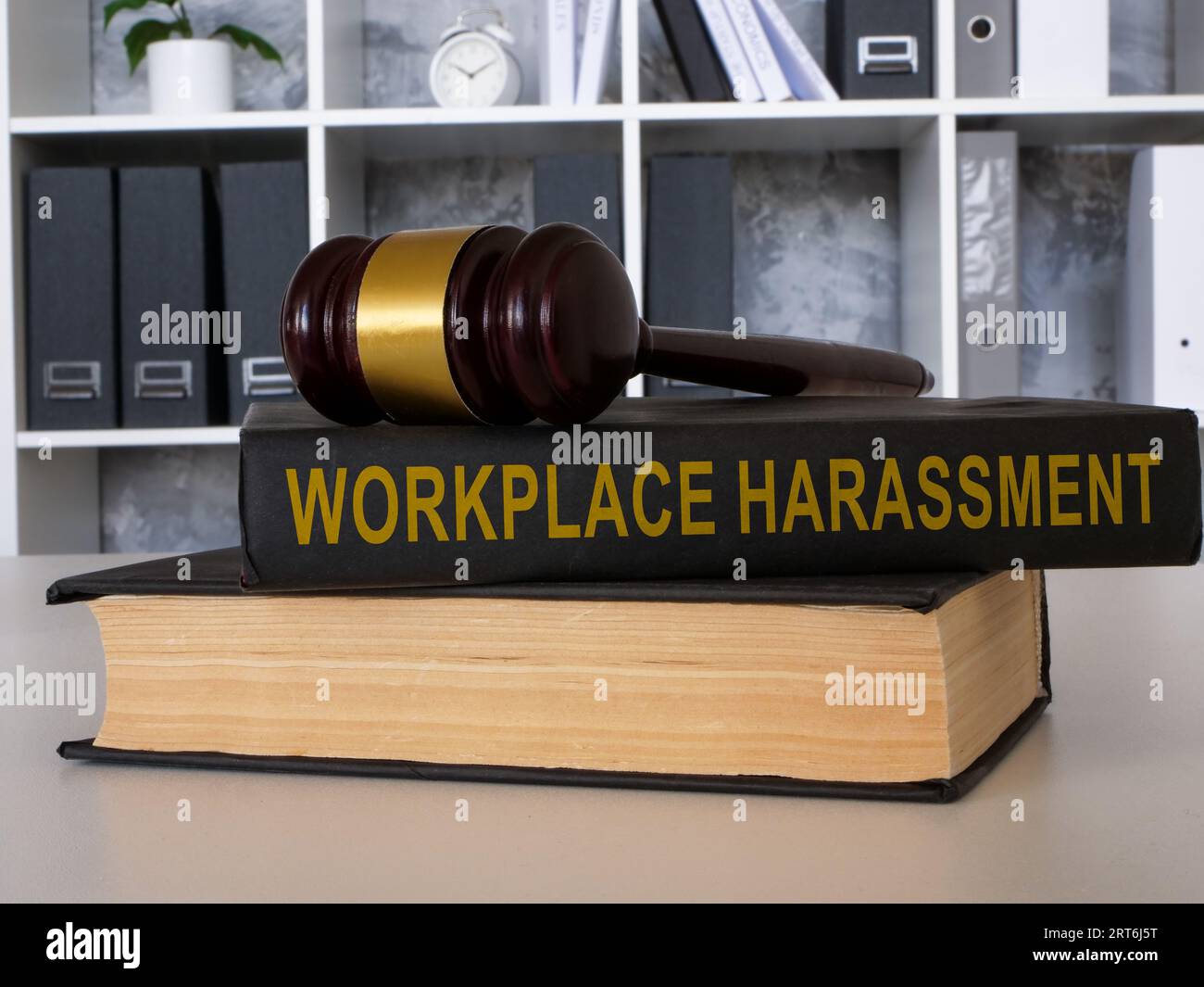 Auf dem Bürotisch liegt ein Buch über die Belästigung des Arbeitsplatzes mit dem Hammer. Stockfoto