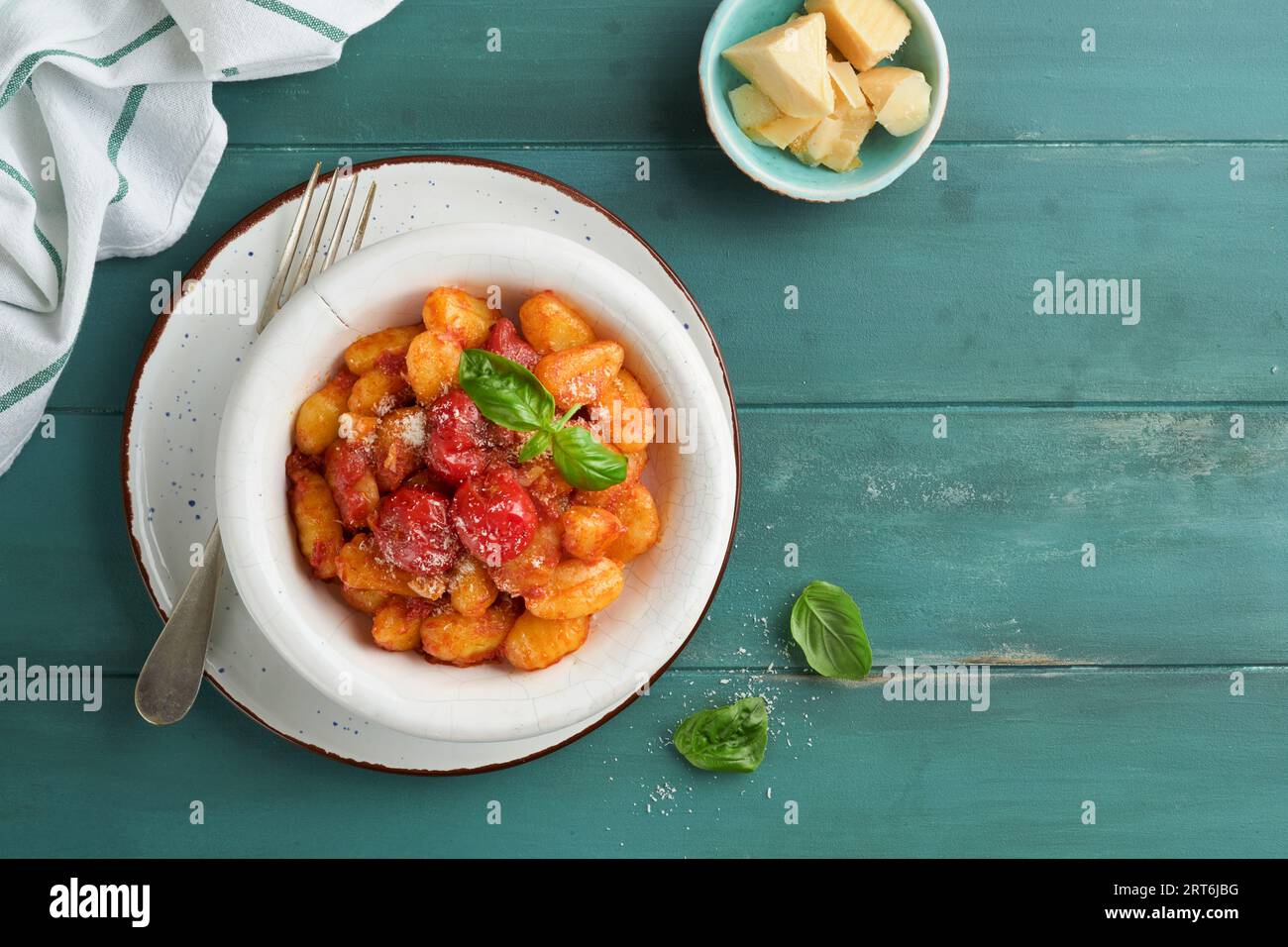 Kartoffelgnocchi. Traditionelle hausgemachte Kartoffelgnocchi mit Tomatensoße, Basilikum und Parmesan auf türkisfarbenem rustikalem Küchentisch. Traditi Stockfoto