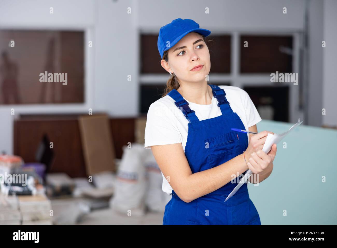 Fokussierte Bauherrin, die Papiere auf der Baustelle im Innenbereich ausfüllt Stockfoto