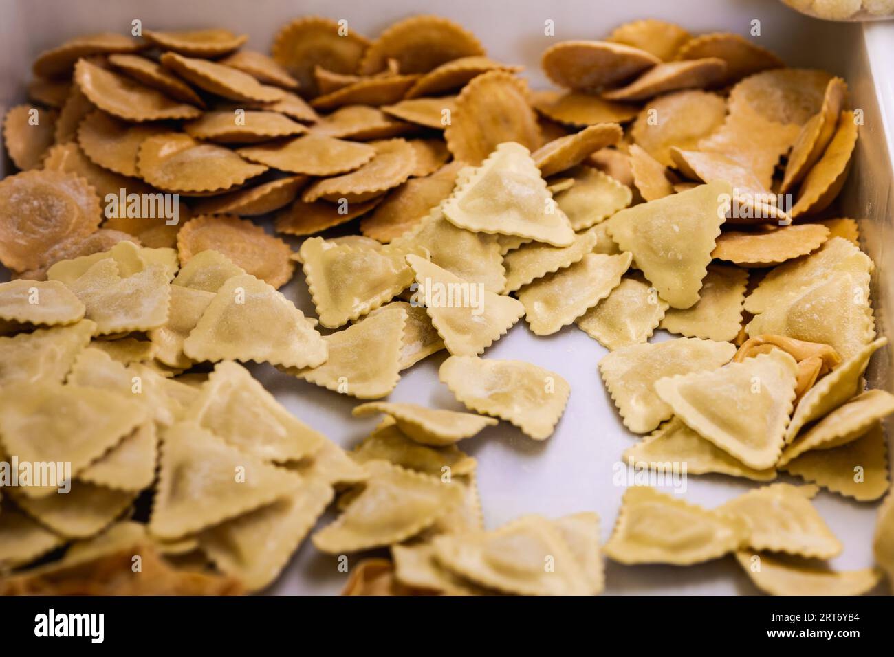 Von oben Nahaufnahme von ungekochten Pasta-Ravioli in verschiedenen Formen, die auf weißem Tisch verteilt sind Stockfoto