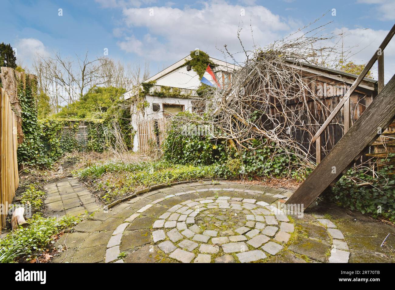 Gepflegte gepflasterter Innenhof mit kleinem Garten in der Nähe von Holzzaun Stockfoto