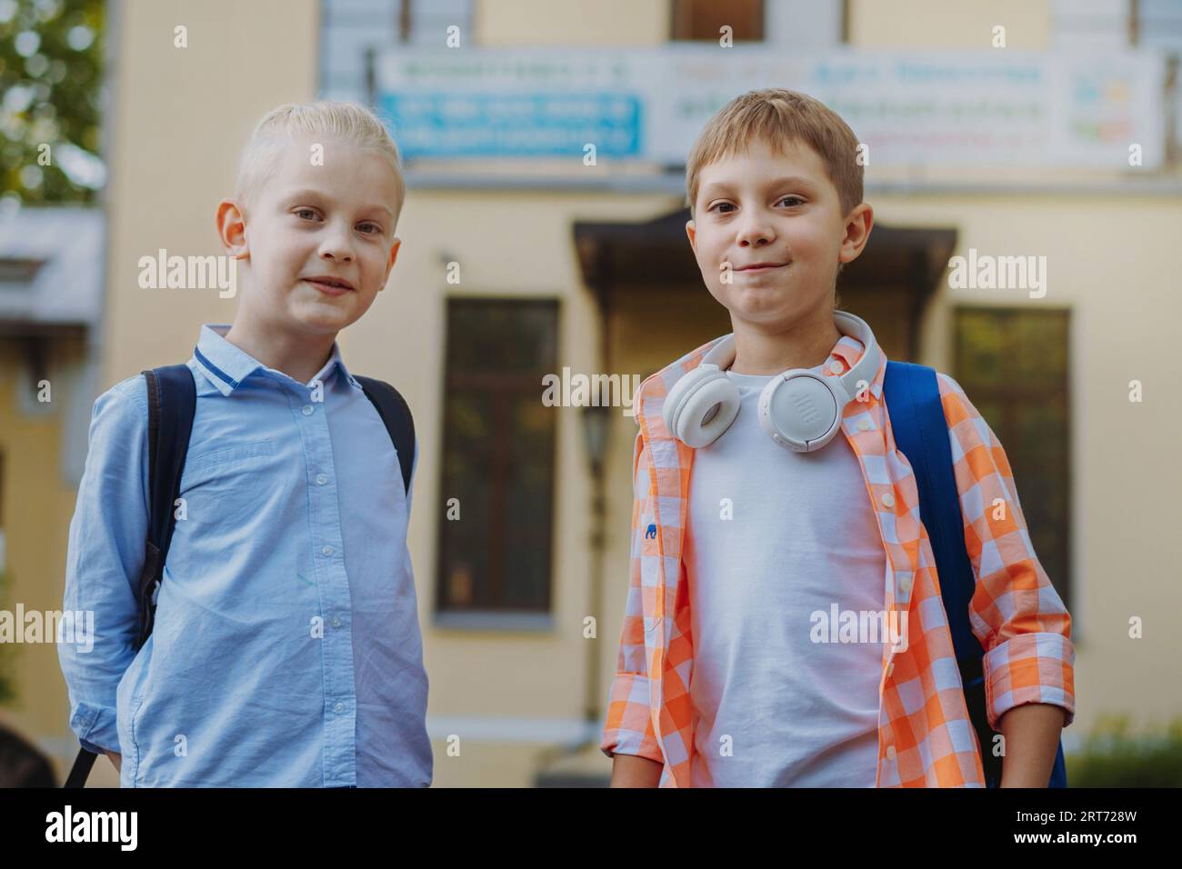 Niedliche kaukasische Kinder vor der Schule mit Rucksäcken an sonnigen Tagen. Beginn des akademischen Jahres. Jungs vor der Tür der Schule. Bild mit selektivem Fokus Stockfoto