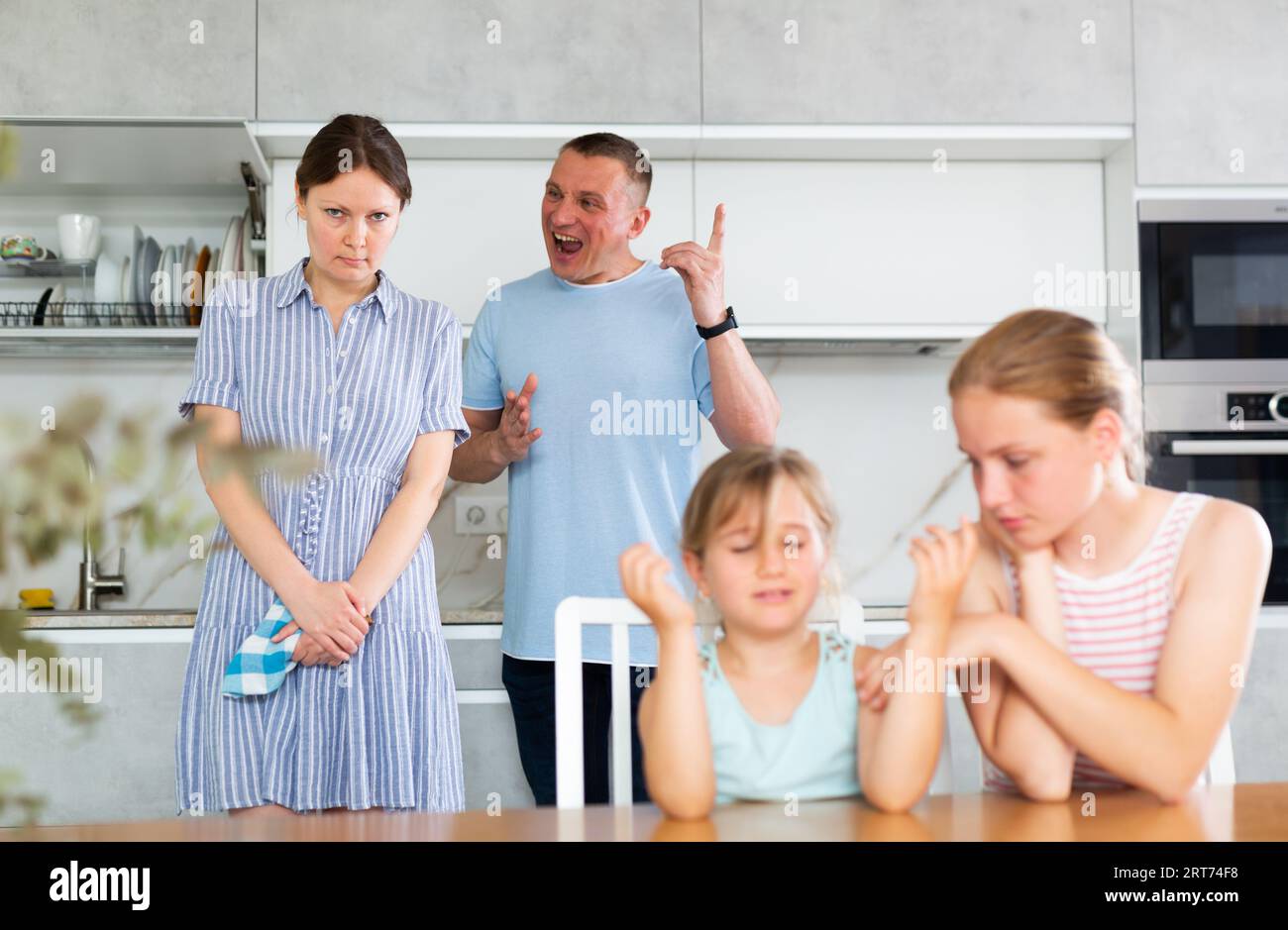 Eltern streiten sich hinter dem Rücken verschwommener, unerkennbarer Kindertöchter. Stockfoto