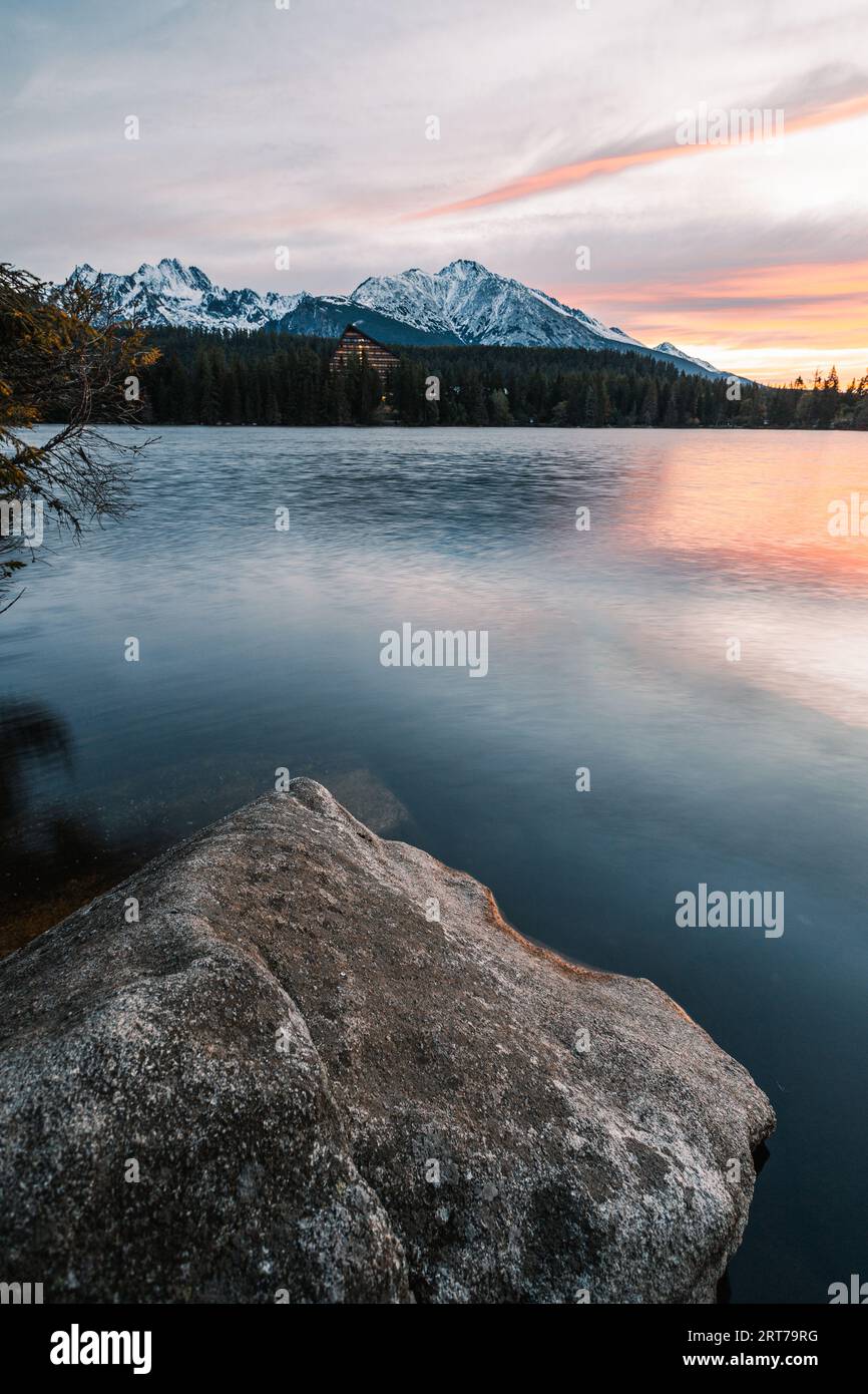 Vertikales Foto eines wunderschönen Sees in Herbstlandschaft mit erstaunlich verschneiten Bergen im Hintergrund. Strbske pleso in der Hohen Tatra im Herbst mit Wasserspiegelung Stockfoto