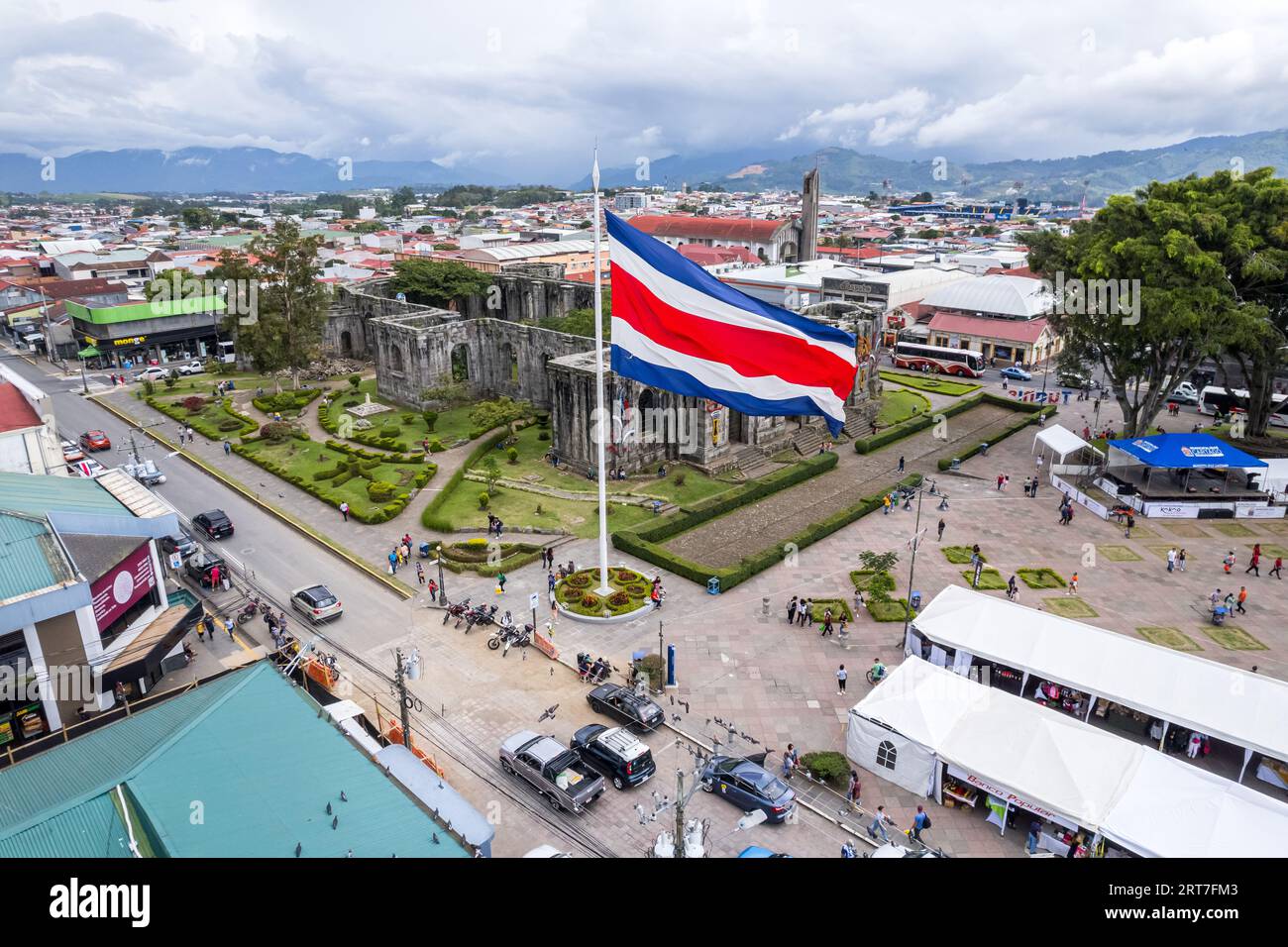 Wunderschöner Blick auf die Costa Rica Flagge mit dem zweihundertjährigen Engel in Cartago, neben den Ruinen und der Basilika - Costa Rica Patriotische Symbole Stockfoto