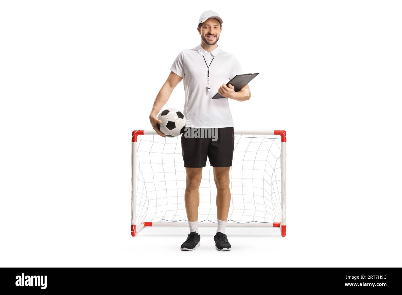 Porträt eines Fußballtrainers, der einen Ball und eine Absteckplatte vor einem Minitor hält, isoliert auf weißem Hintergrund Stockfoto