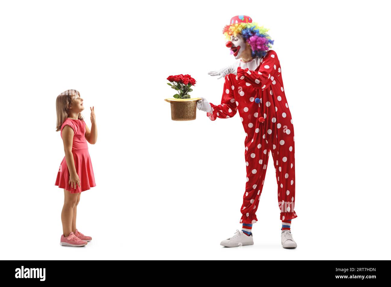 Profilaufnahme in voller Länge eines Mädchens, das einen Clowns beobachtet, der einen Trick auf weißem Hintergrund spielt Stockfoto