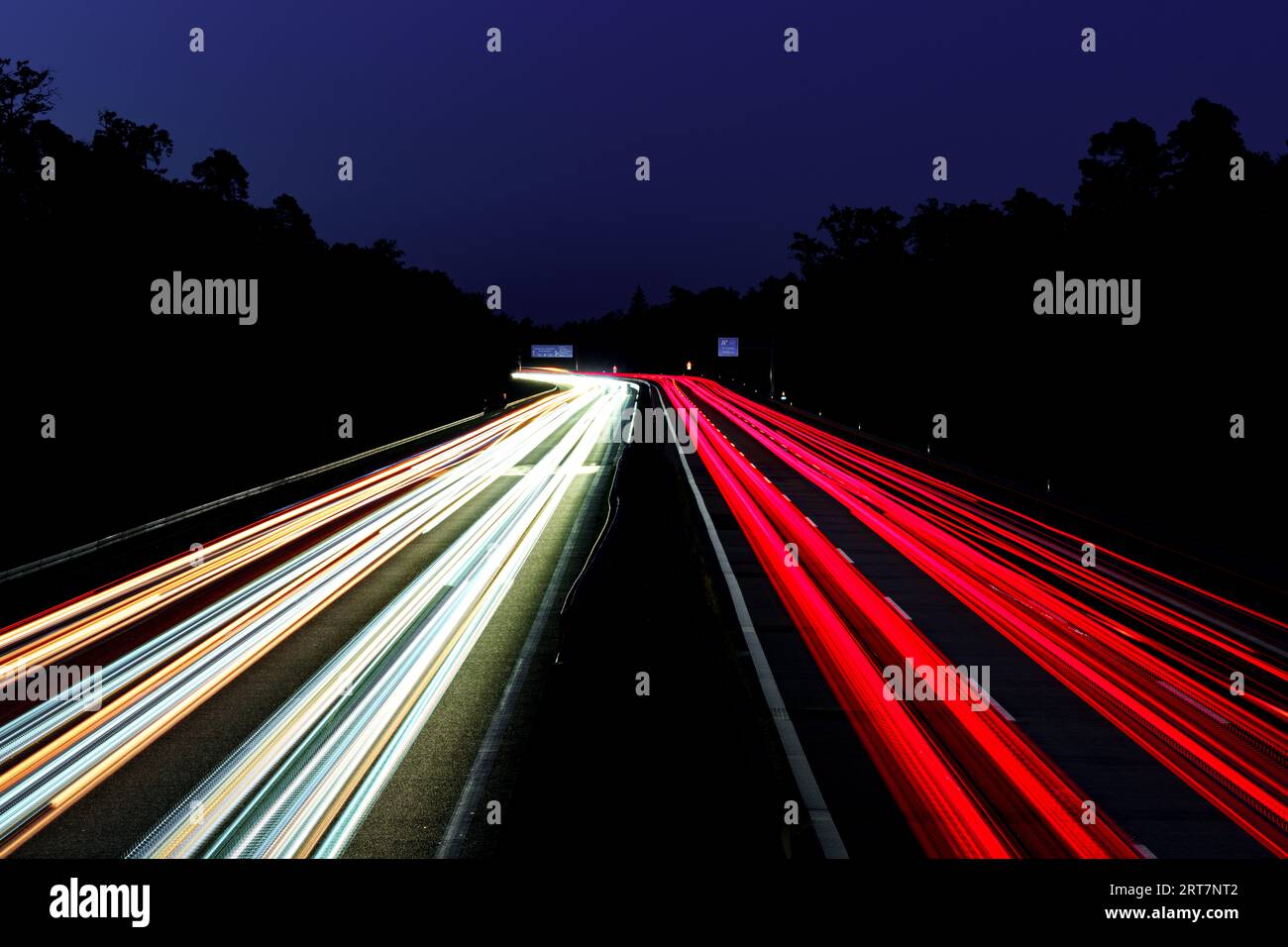 Leichte Autowege. Lichter auf der Autobahn. Spuren von Autos. Abstraktes Licht, Lichtschweife. Highway bei Sonnenuntergang und viel Verkehr. Autobahn bei Nacht. Stockfoto