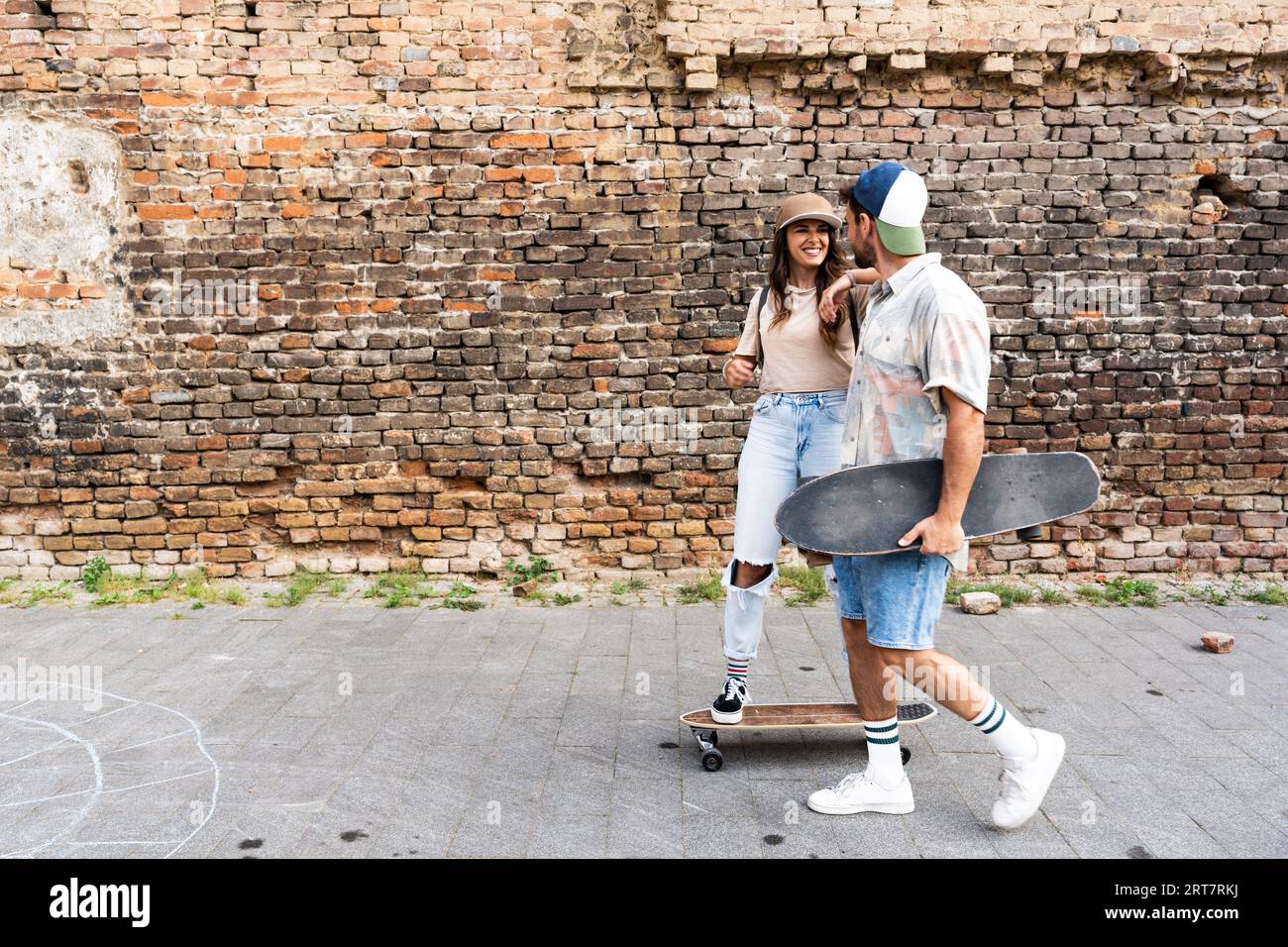 Porträt eines jungen Paares mit Skateboard und Longboard mit Spaß im Freien. Mann und Frau, Freund und Freundin, die Schlittschuhlaufen genießen Stockfoto