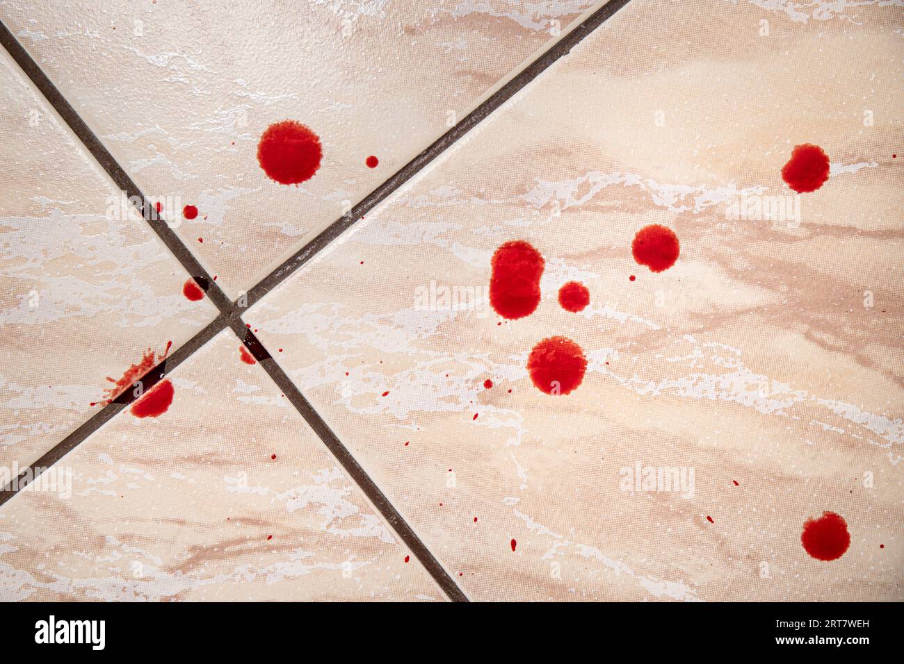 Echte frische rote Bluttropfen auf dem Badezimmerboden zu Hause. Verletzungs- oder Kriminalitätskonzept. Stockfoto