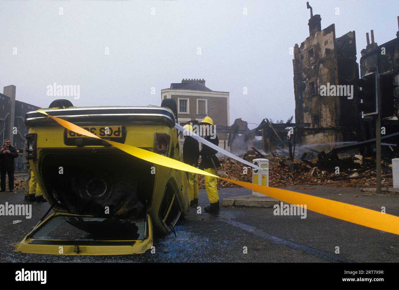 Brixton stößt in den 1980er Jahren auf Großbritannien auf. Am Tag nach der Feuerwehrauto, um sicherzustellen, dass die brennenden Gebäude völlig sicher sind. Verbrannte zerstörte Gebäude, entführte Burnout-Auto. Brixton South London Großbritannien April 1981 England HOMER SYKES. Stockfoto