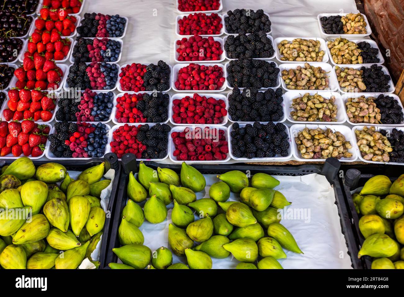 Weiße Tabletts mit Erdbeeren, Himbeeren, Brombeeren, Blaubeeren, dunklen Kirschen und weißen Maulbeeren füllen einen Obststand in der Altstadt von Tiflis, Georgien, wahrscheinlich in der Kote-Abkhazi-Straße. Grüne Feigen liegen in schwarzen Kisten davor. Die Kote-Abkhazi-Straße hieß früher Leselidze-Straße. Sie verläuft vom Freiheitsplatz zum Meidan-Platz und war einst eine Karawanenroute. Stockfoto