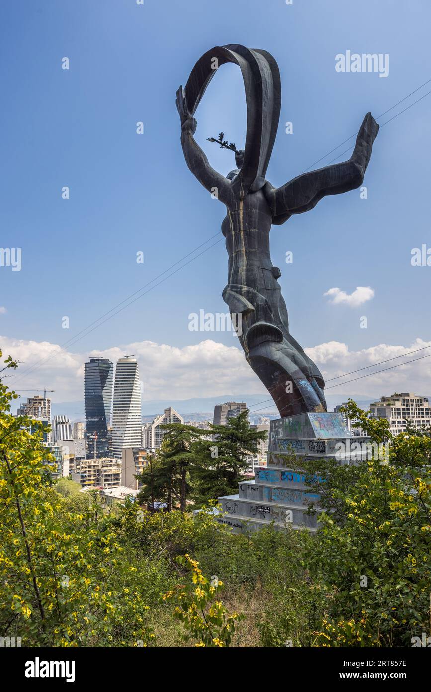 Die Statue einer Frau steht auf einem Sockel an der Gedenkstätte für das Grab des unbekannten Soldaten in Vake, Tiflis, Georgien, Europa. Ihre Arme sind hoch. Sie hält einen Zweig in der linken Hand und einen Schal in der rechten Hand. Der Sockel ist mit Graffiti bedeckt. Eine Treppe führt zum Sockel Stockfoto