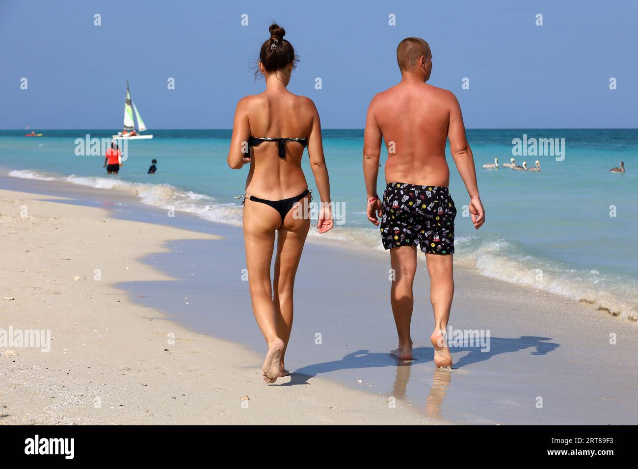 Ein Paar, das am Sand auf dem Meeresgrund spaziert. Sonniger Strand mit Touristenresort Stockfoto