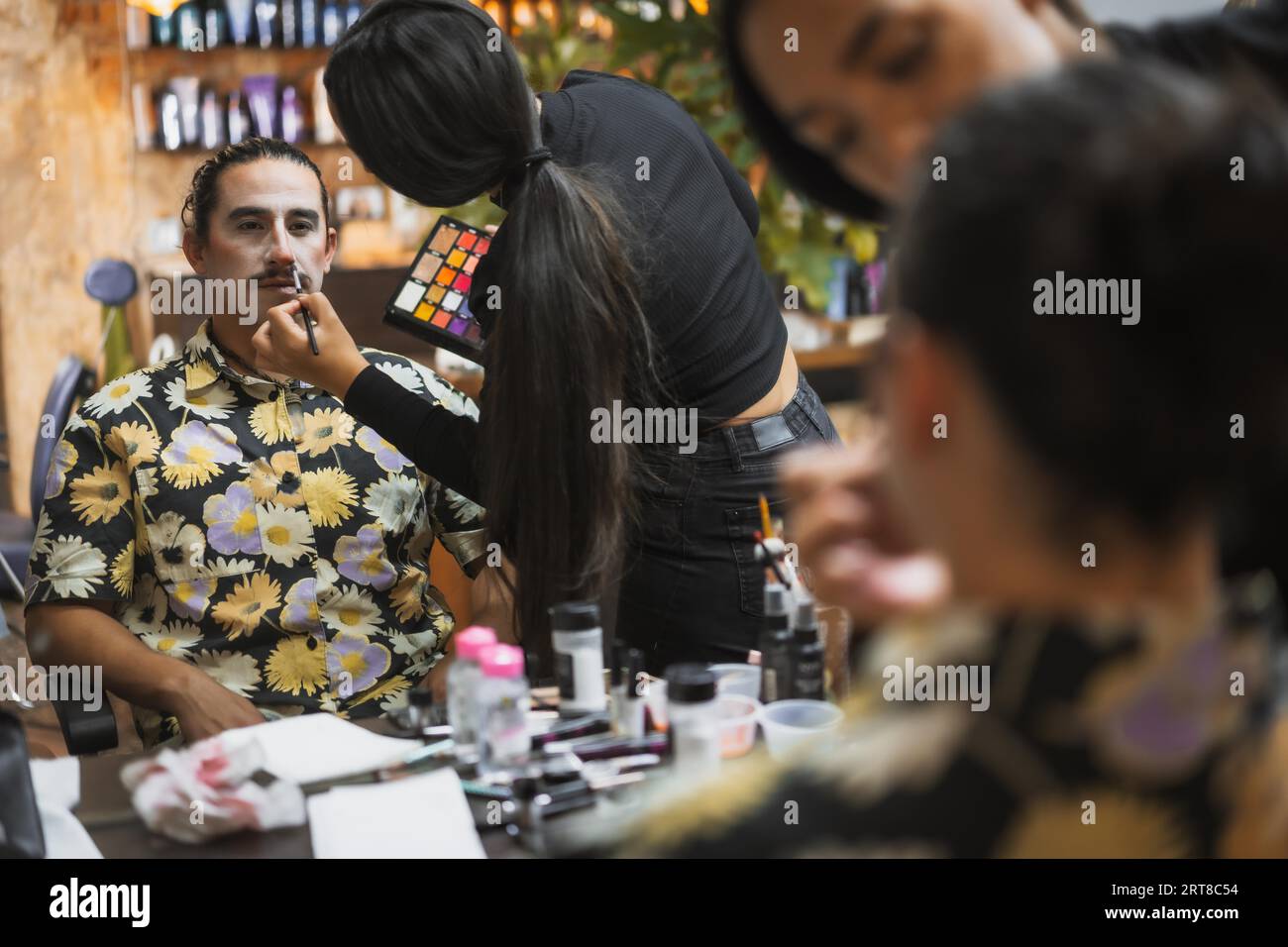 Halloween-Party-Frisur und Make-up-Vorbereitungen, Make-up-Künstler, der einen Mann mit weißer Farbe macht Stockfoto