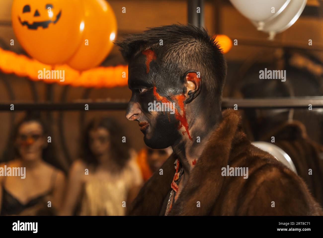 Halloween-Party mit Freunden in einem Disco-Nachtclub, Porträt eines Mannes im Kostüm mit bemaltem Bett Stockfoto