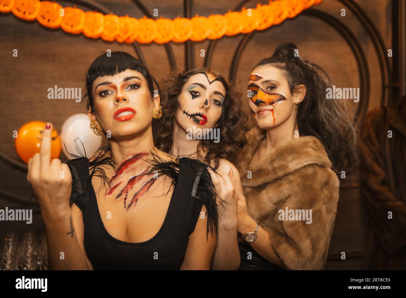 Weibliche Freunde in Kostümen auf der halloween-Party mit Freunden in Disco-Nachtklub und Blick auf die Kamera Stockfoto