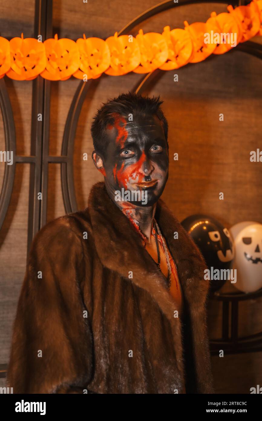 Halloween-Party mit Freunden in einem Disco-Nachtclub, Porträt eines Mannes mit einem verbrannten und blutigen Gesicht Stockfoto
