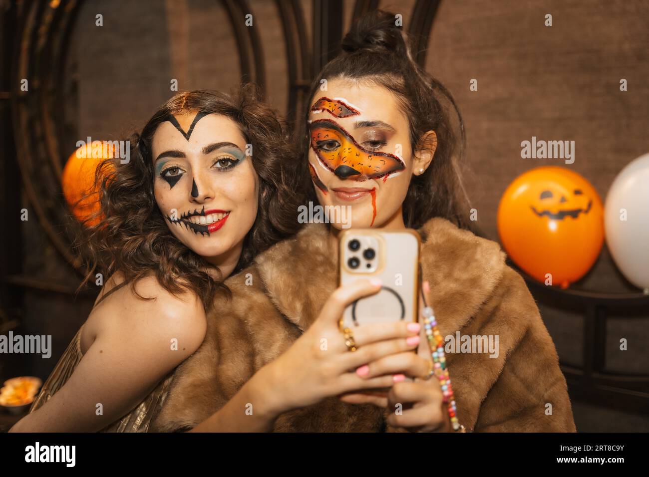 Freundinnen in Kostümen auf der halloween-Party mit Freunden in einem Disco-Nachtclub Stockfoto