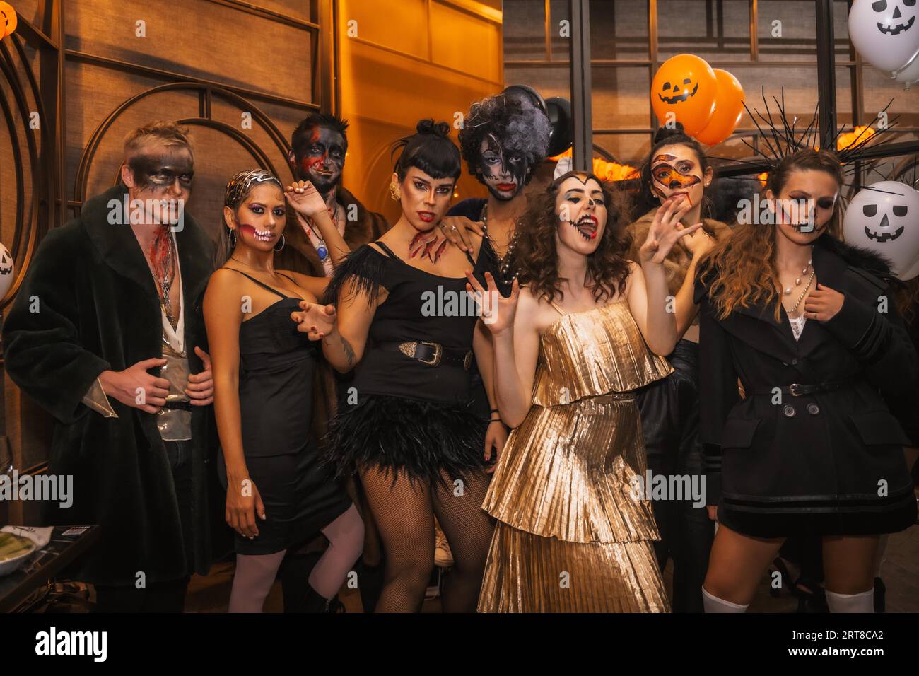 Halloween-Party mit Freunden in einem Disco-Nachtclub, eine Gruppe von Freunden sitzt auf einem Sofa in Make-up und Kostümen Stockfoto