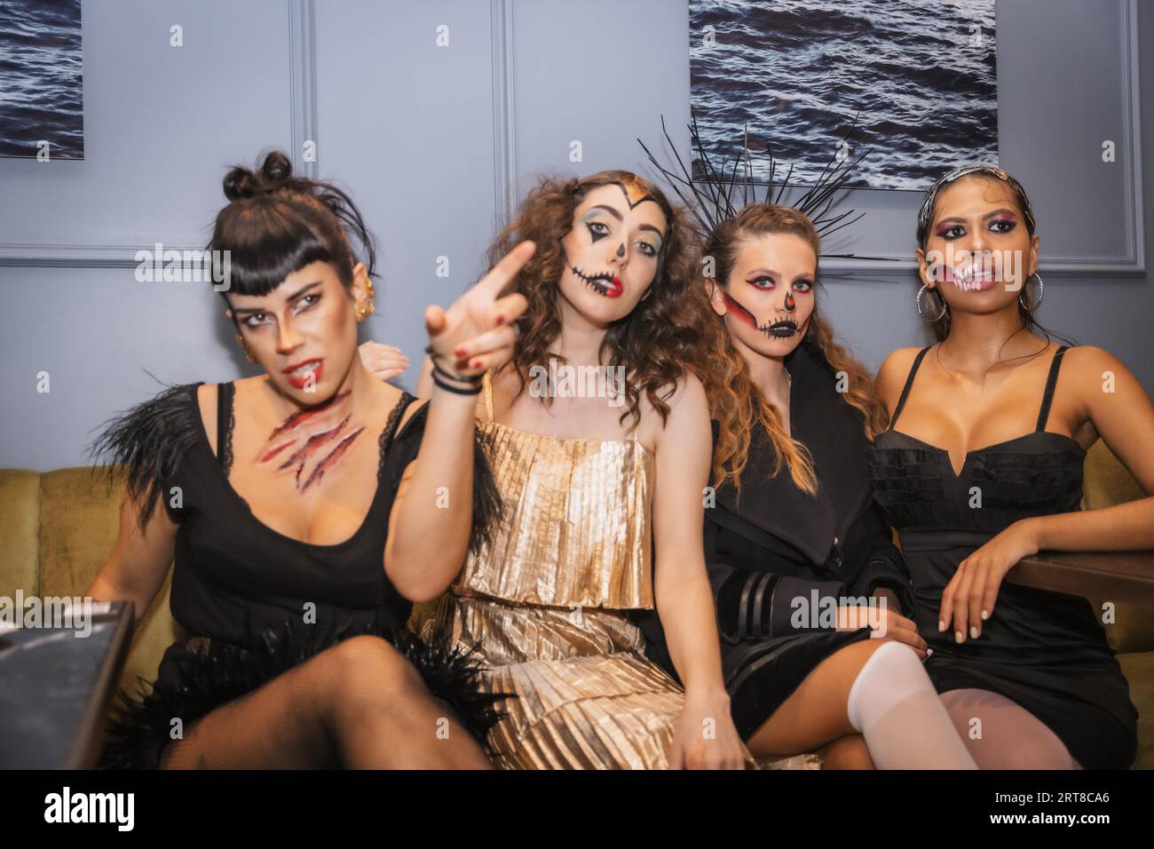 Halloween-Party mit Freunden in einem Disco-Nachtclub, Porträt einer Gruppe weiblicher Freunde, die auf einem Sofa mit Make-up sitzen Stockfoto