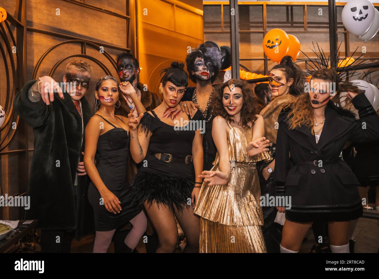 Halloween-Party mit Freunden in einem Disco-Nachtclub, einer multiethnischen Gruppe von Freunden, die auf einem Sofa in Make-up und Kostümen sitzen Stockfoto