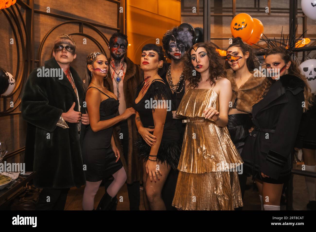 Halloween-Party mit Freunden in einem Disco-Nachtclub, Porträt einer Gruppe von Freunden, die auf einem Sofa in Make-up und Kostümen sitzen Stockfoto