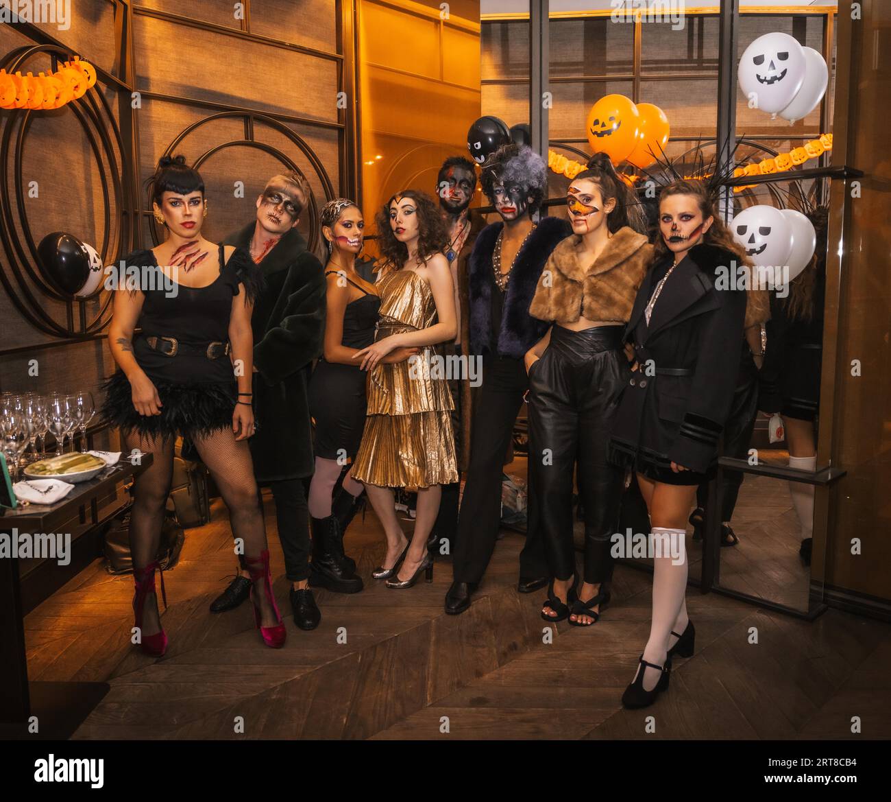 Halloween-Party mit Freunden in einem Disco-Nachtclub, Porträt einer Gruppe von Freunden, die auf einem Sofa in Make-up und Kostümen sitzen Stockfoto