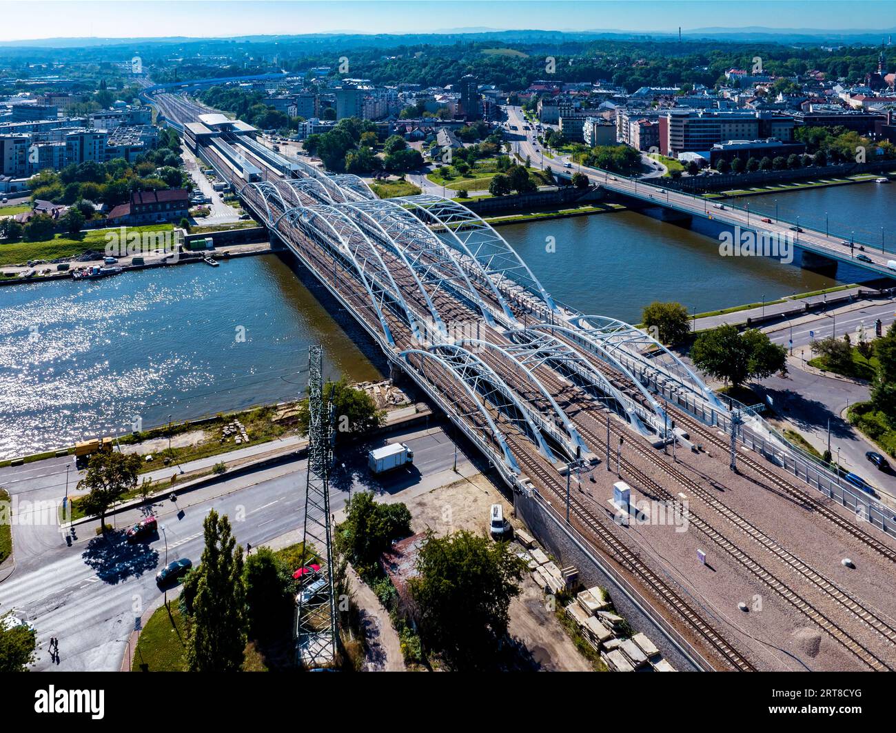 Neue dreifach gebundene Eisenbahnbrücke mit vier Gleisen, Fußgängerbrücke und Fahrradroute über die Weichsel in Krakau, Polen. Fernblick auf das neue Krakauer Zabloci Stockfoto
