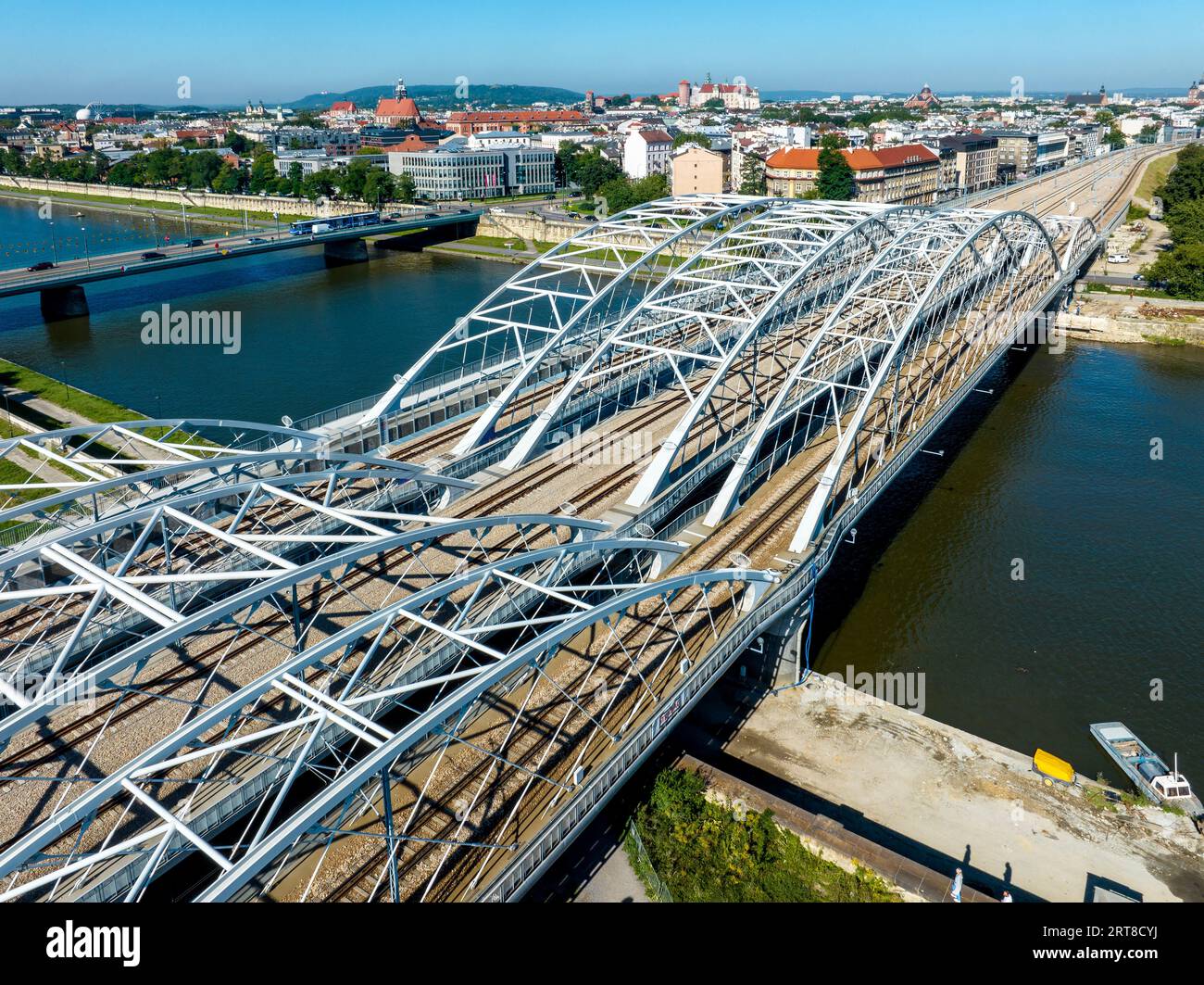 Neue dreifach gebundene Eisenbahnbrücke mit vier Gleisen über die Weichsel in Krakau, Polen. Eine weitere Brücke mit Autos und Straßenbahn. Altstadt mit Wawel-Guss Stockfoto