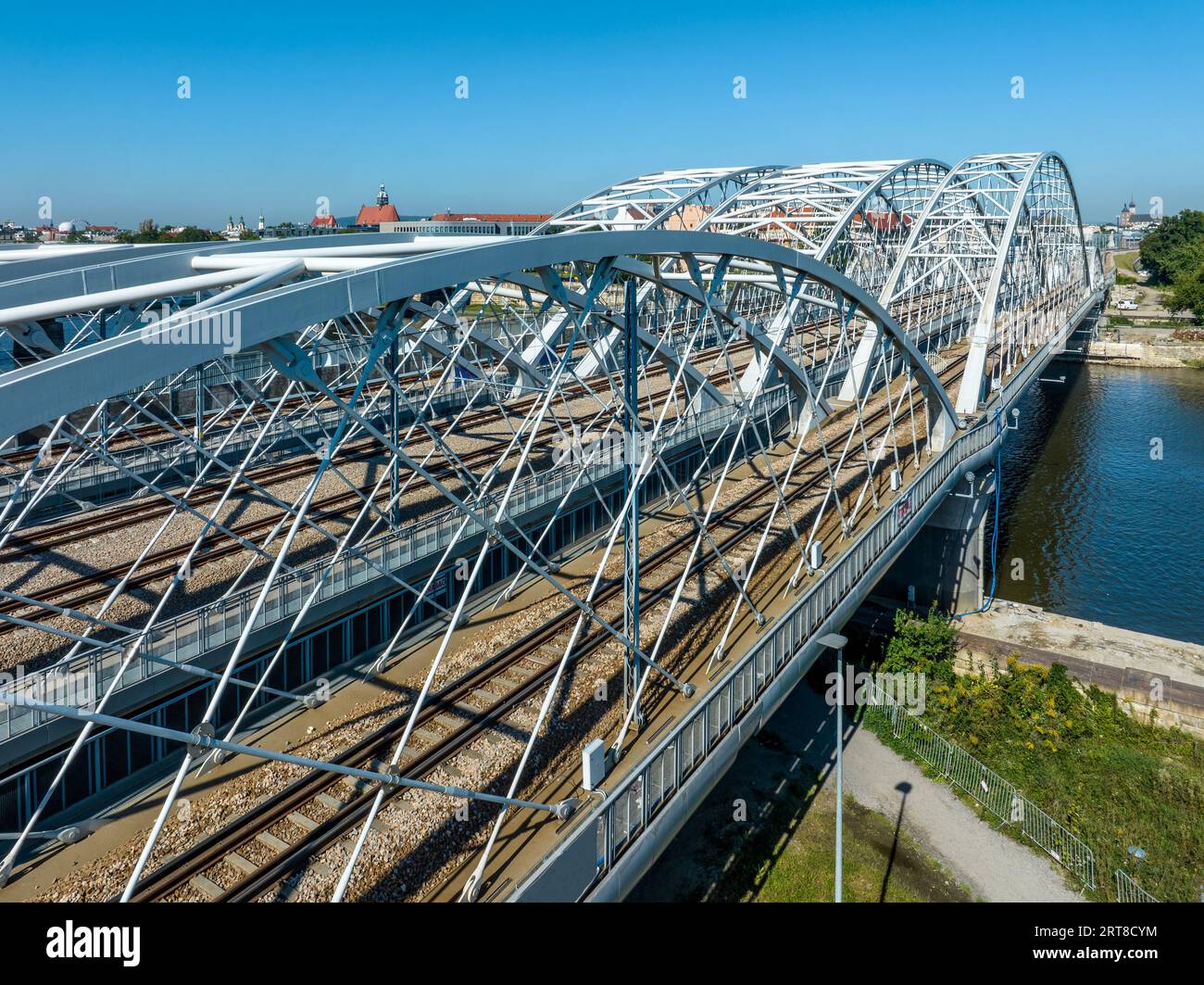 Dreifach gebundene Eisenbahnbrücke mit vier Gleisen über die Weichsel in Krakau, Polen. Altstadt im Hintergrund. Drohnenansicht aus der Luft. Stockfoto
