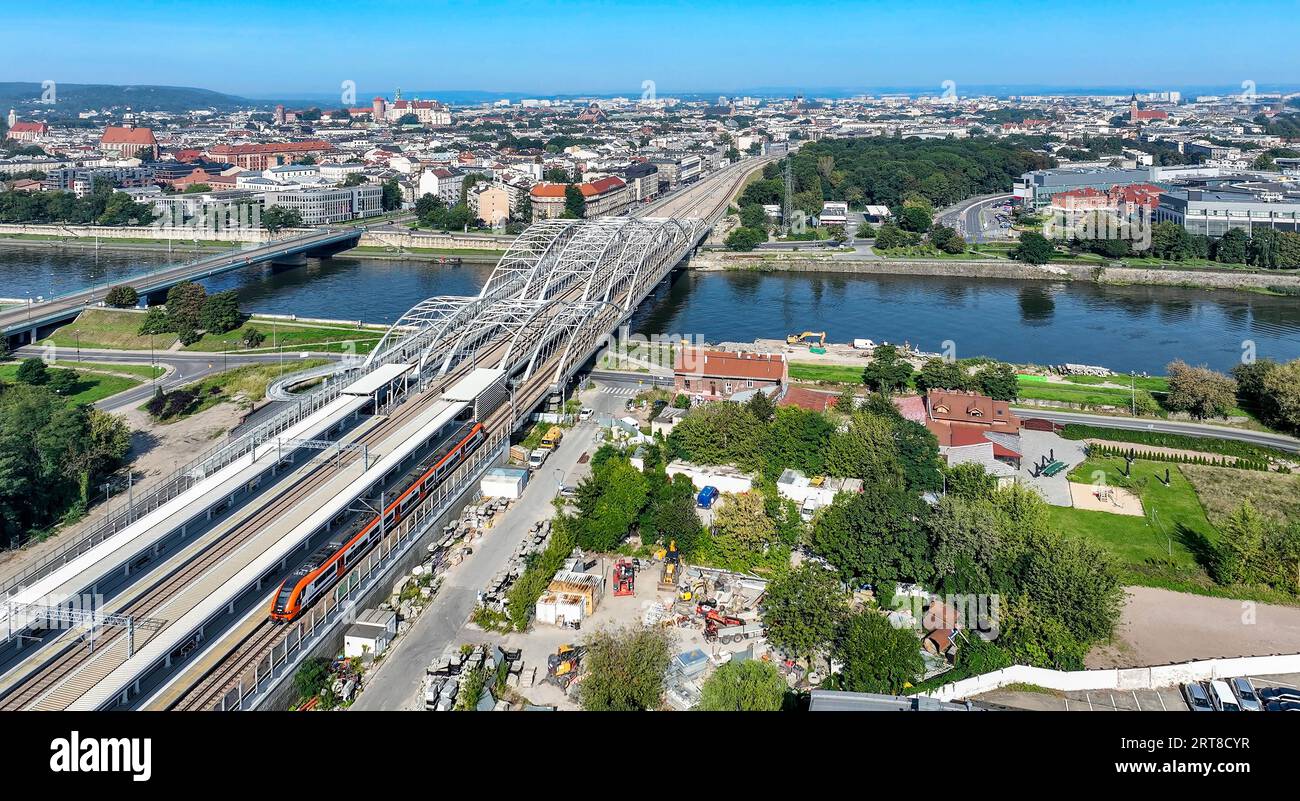 Schneller Stadtzug, neuer Bahnhof Krakau Zablocie und neue dreifach gebundene Bogenbahnbrücke mit vier Gleisen, Fußgängerbrücke und Radweg über die Weichsel Stockfoto
