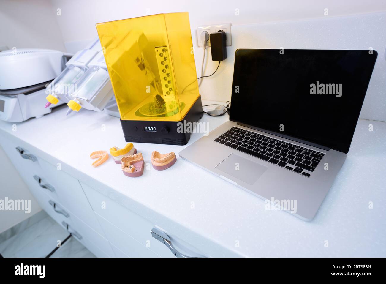 Laptop und Gerät zum Waschen eines Dental 3D Prints in einer Reinigungslösung und zum Aushärten der Form mit UV-Licht. Stockfoto