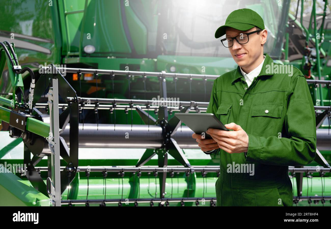 Landwirt mit digitalem Tablet auf dem Hintergrund des Erntemaschinen. Intelligentes Landwirtschaftskonzept... Stockfoto