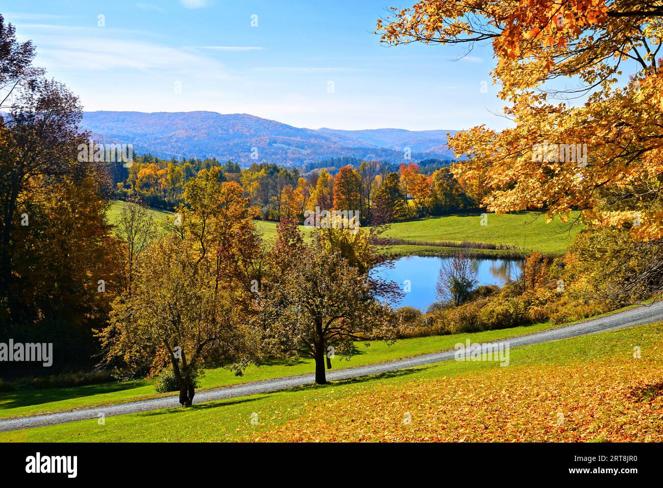 Bunte herbstliche Landschaft mit Bergen und Teich unter blauem Himmel in der Nähe von Woodstock, Vermont, USA Stockfoto