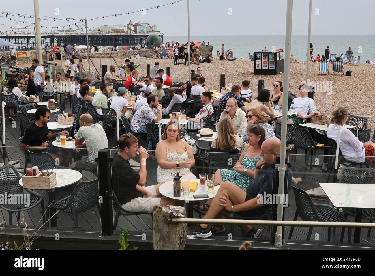 Gruppen von Menschen, die im Sommer in einer Bar am Brighton Seafront trinken Stockfoto
