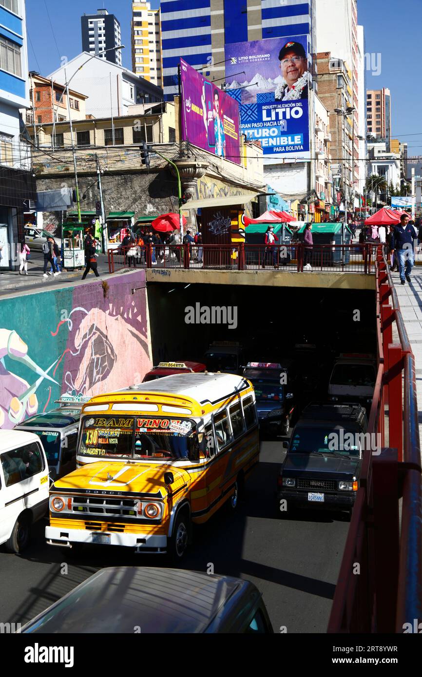 La Paz, BOLIVIEN; 11. September 2023: Ein alter öffentlicher Kleinbus im Av Villazon-Tunnel, mit dem bolivianischen Präsidenten Luis Arce Catacora auf einer Horde, die die "Industrialisierung von Lithium, einen großen Schritt in Richtung einer nachhaltigen Zukunft für Bolivien" im Hintergrund fördert. Bolivien verfügt über einige der größten Lithiumreserven der Welt in der Salar de Uyuni-Saline, deren Entwicklung für die Wirtschaftspolitik der Regierung von zentraler Bedeutung ist. In diesem Jahr hat Bolivien mit dem chinesischen Batteriehersteller CATL und der Citic Guoan Group und dem russischen Staatsunternehmen Rosatom Vereinbarungen zur Entwicklung dieser Ressourcen unterzeichnet. Stockfoto