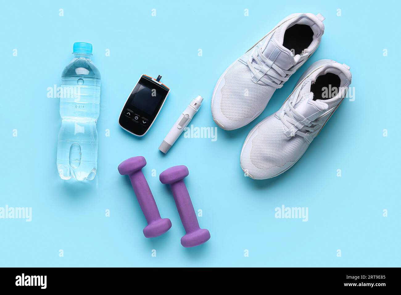 Glucometer, Turnschuhe, Kurzhanteln, Wasserflasche und Lanzette auf blauem Hintergrund. Diabetes-Konzept Stockfoto