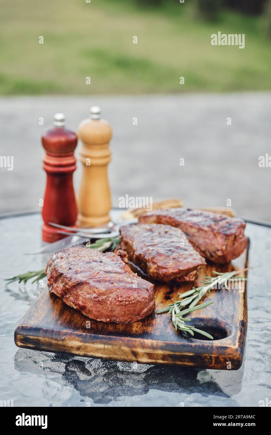 Gegrillte New York Strip Steaks auf dem Glastisch im Hinterhof Stockfoto