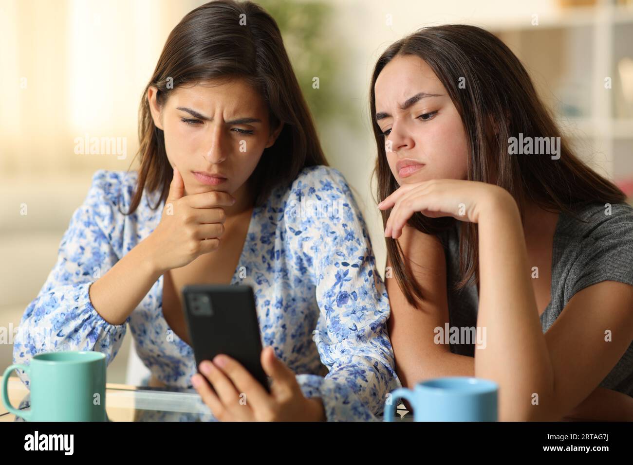 Enttäuschte Frauen, die zuhause am Telefon Medien sehen Stockfoto