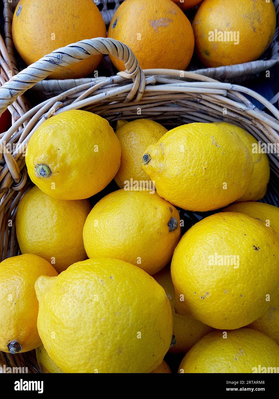 Detail von Körben mit Orangen und Zitronen auf einem Holztisch. Stockfoto